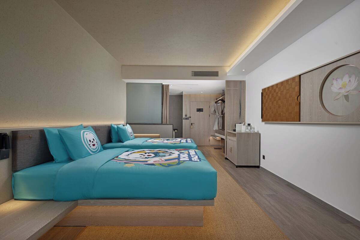 A modern hotel room with a large bed, a bedside table, a mirror, and a wardrobe.