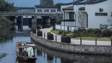 A traditional boat with passengers, a bridge, and a modern building with a sign.