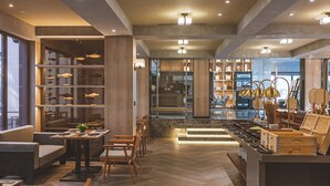 A modern interior with a central dining area, wooden furniture, and a kitchen counter with various items. - Wanda Moments Xitang (Jiaxing)