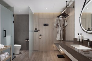 A modern bathroom with a wooden vanity, a large mirror, and a towel rack.