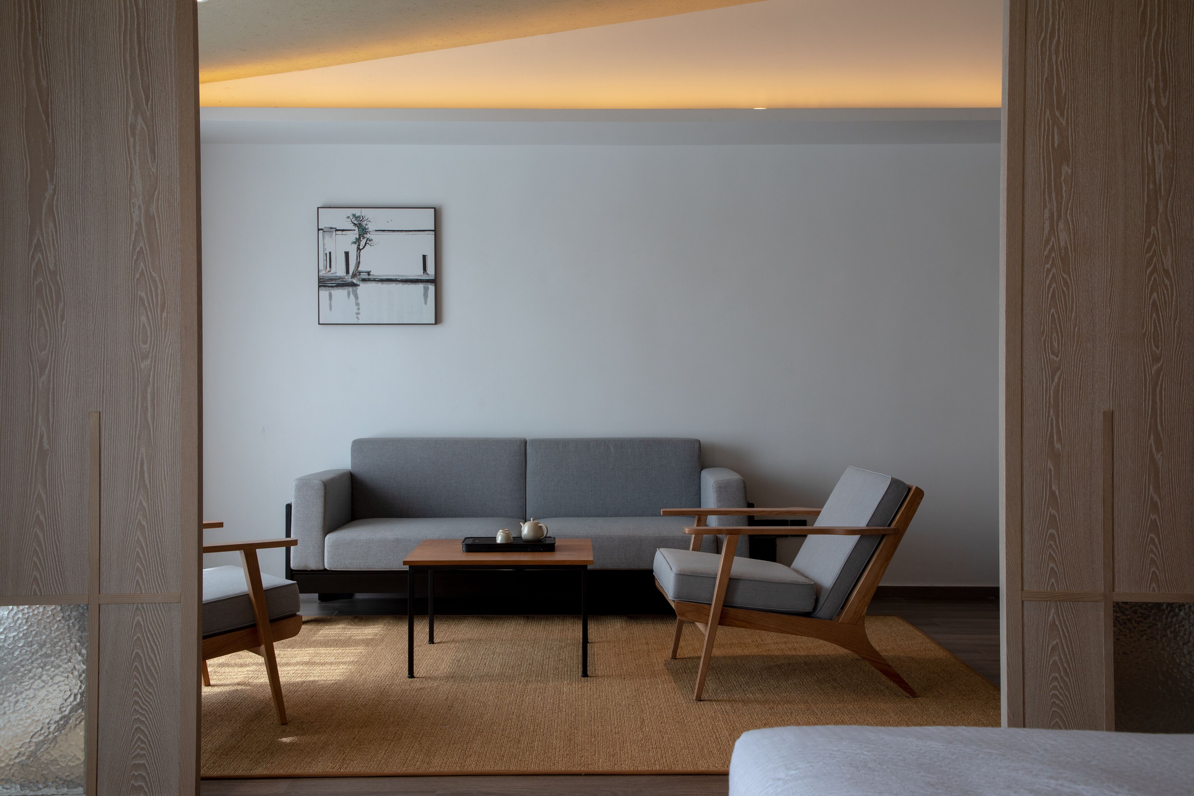 Una sala de estar moderna con un sofá gris, una mesa de centro de madera y un sillón de madera.
