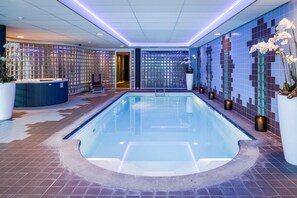 Relax by the pool surrounded by a vibrant mosaic wall and a reception area.