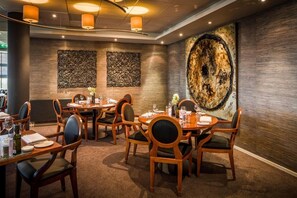 Enjoy a sophisticated dining experience with round tables, comfortable seating, and elegant decor.