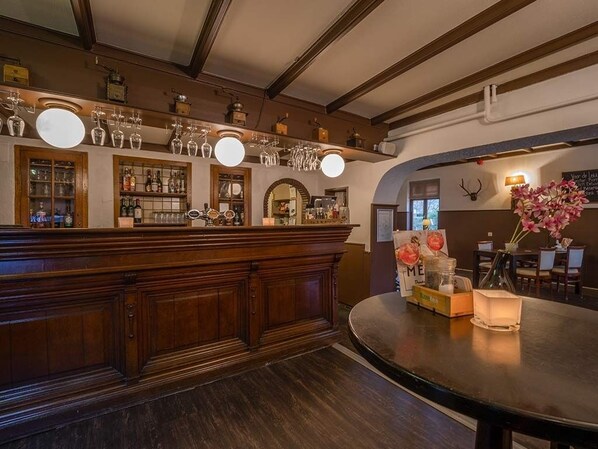 Enjoy a classic bar experience with a wooden counter, shelves, and exposed beams.