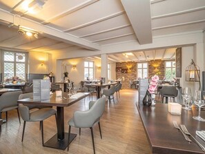 Enjoy meals in this elegant dining area with high ceilings, exposed beams, and beautifully set tables.