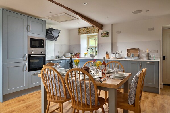 A modern kitchen with grey cabinets, a wooden dining table, and chairs.