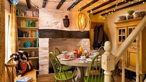 Ein gemütlicher Essbereich mit einem Holztisch, grünen Stühlen und einem Bücherregal voller Bücher.