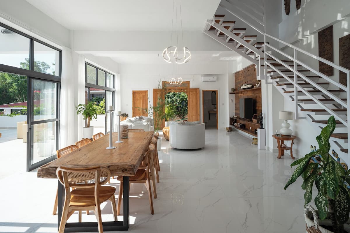 A spacious, modern kitchen with a central island, a dining area with a wooden table and chairs, and a staircase leading to an upper level.