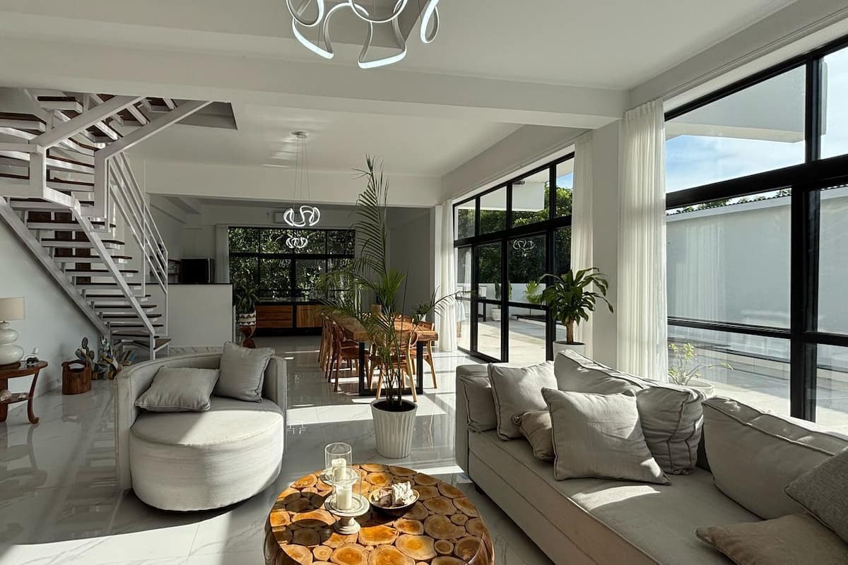 A spacious living area with a modern staircase, a large window offering a view, and a cozy seating arrangement.