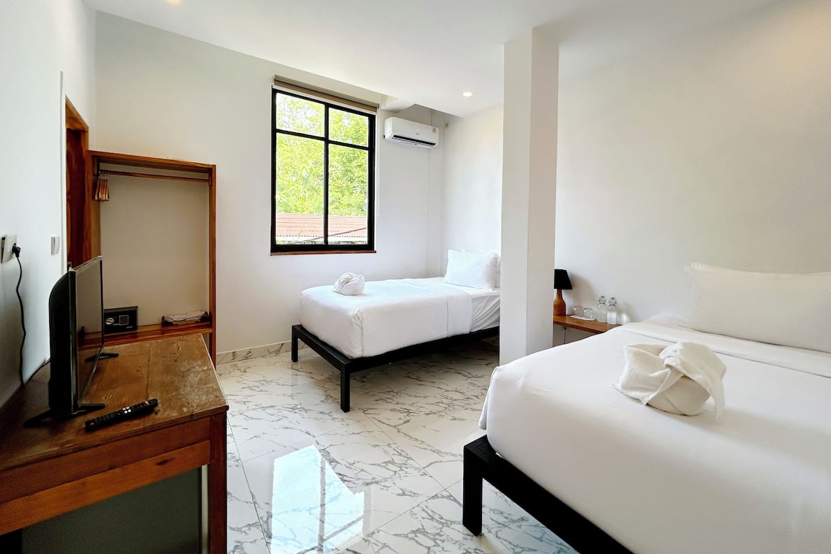 A hotel room with a bed, a TV, a desk, and a window.