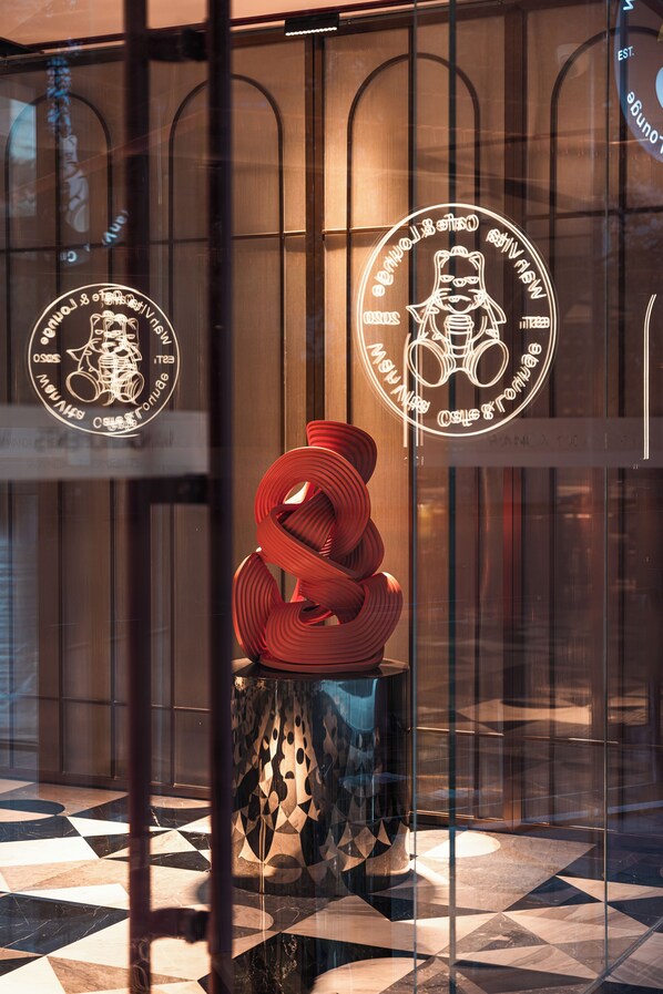 A modern interior with a geometric patterned floor and a glass partition with circular logos. - Wanda Moments Xi'an Bell Tower (Xi'an)