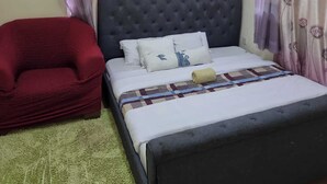 Une chambre à coucher avec un lit, une chaise rouge et un ventilateur de plafond.