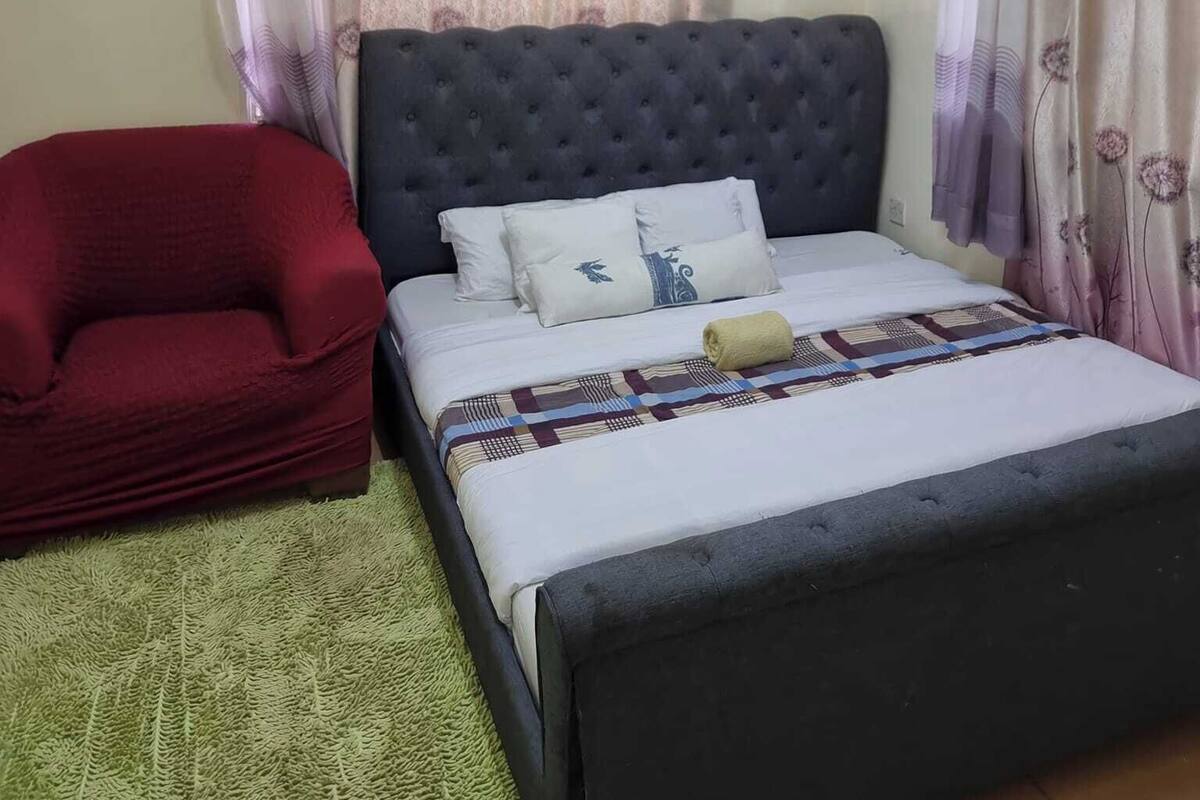A bedroom with a bed, a red chair, and a ceiling fan.