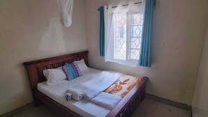 Un lit simple avec une tête de lit en bois, une literie blanche et une couverture à motifs floraux.