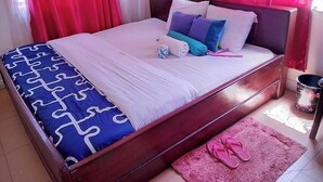 Un lit bien fait, avec une couvre-lit à motifs, des oreillers et une serviette enroulée.