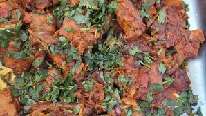 Une vue rapprochée d’un plat composé de morceaux de viande et d’une sauce rouge et onctueuse, agrémenté d’herbes vertes.