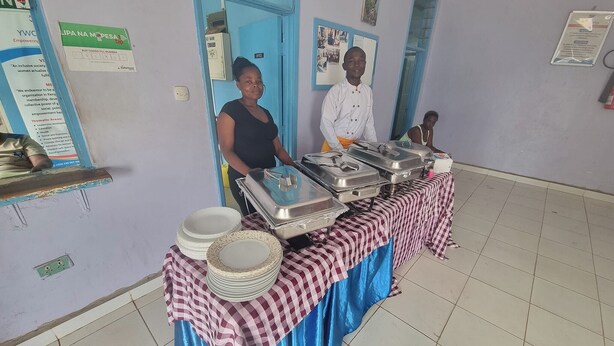 Un buffet avec plusieurs plateaux de service et des piles d’assiettes disposées sur une nappe à carreaux.
