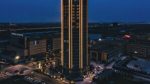 Un hotel alto de diseño moderno, con una llamativa franja vertical de luces y un letrero en la parte superior.