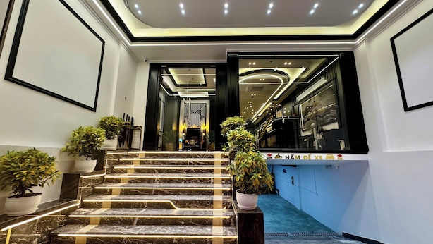 A hotel reception area with marble steps, potted plants, and a blue carpet. - Royal Hanoi Hotel  (Hanoi)
