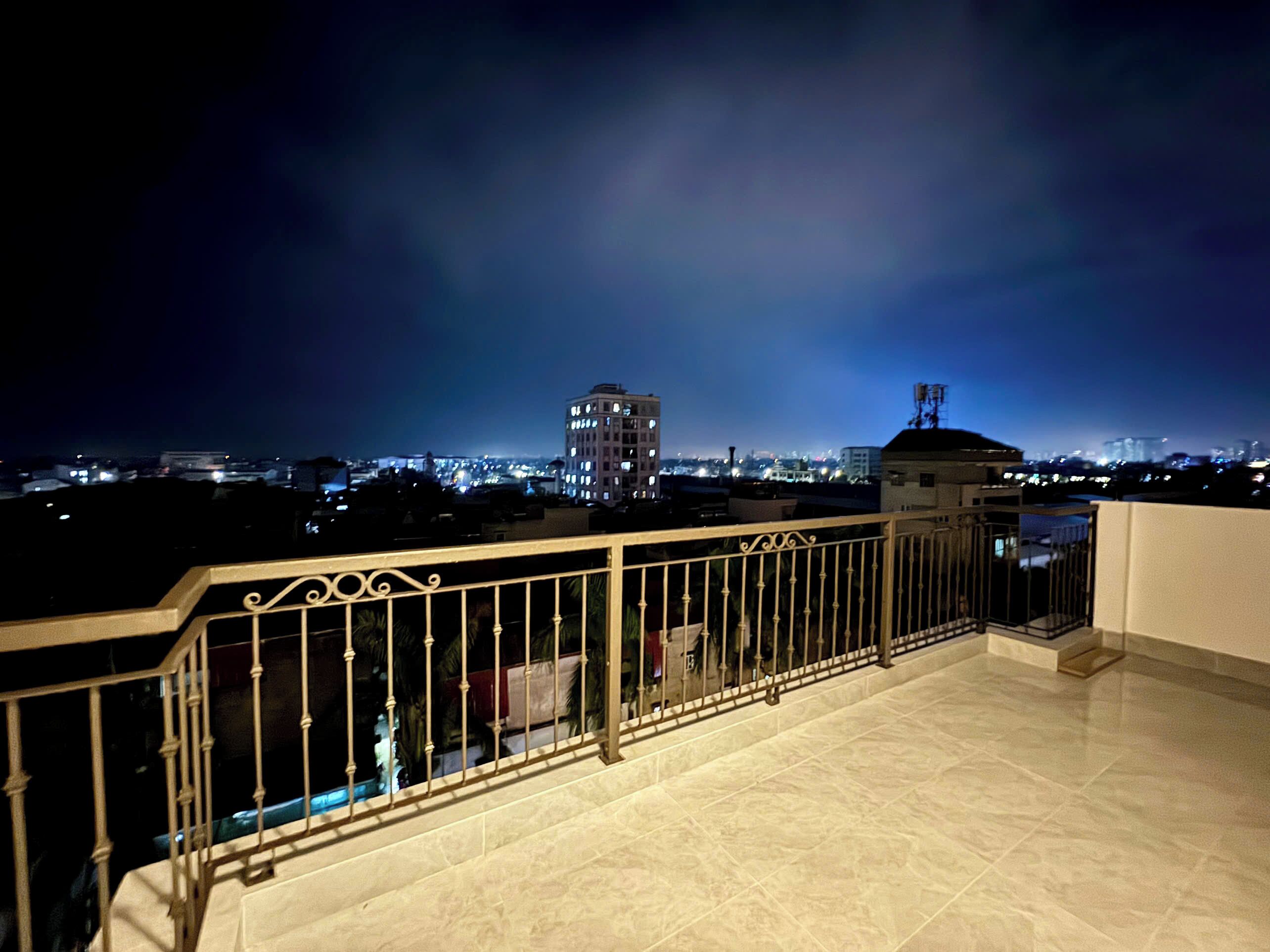 Un balcón con barandilla metálica que da a una vista nocturna de la ciudad.