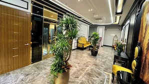A modern lobby with marble flooring, a reception desk, and a seating area with yellow chairs. - Royal Hanoi Hotel  (Hanoi)