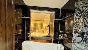 A modern bathroom with a freestanding bathtub, a mirror, and a shower area. - Royal Hanoi Hotel  (Hanoi)