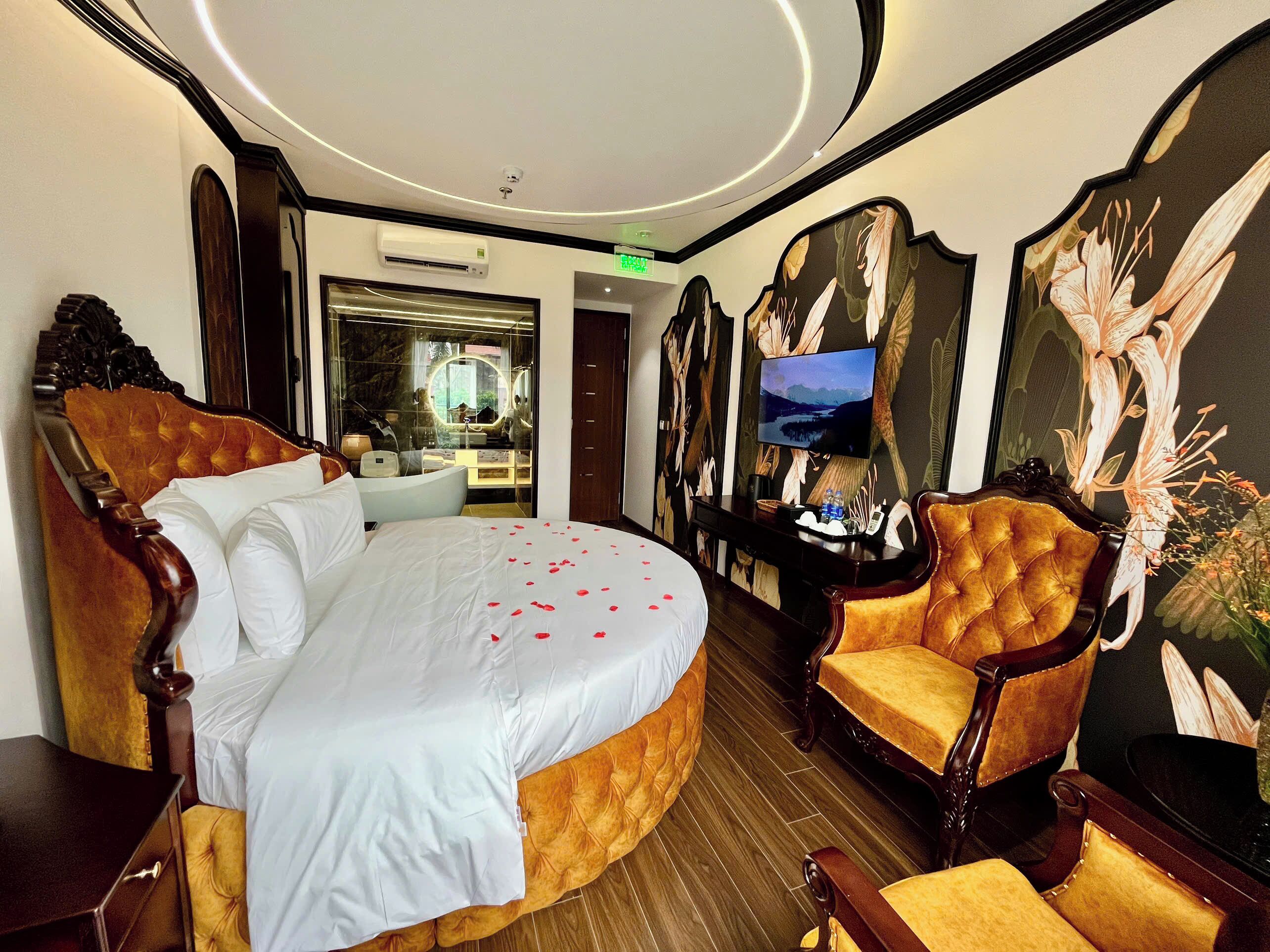 A hotel room with a large bed, a sitting area with a chair, a television, and a mirror.