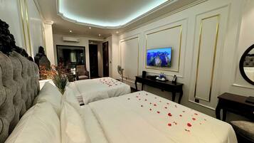 Quarto de hotel com duas camas, televisão, escrivaninha e espelho.