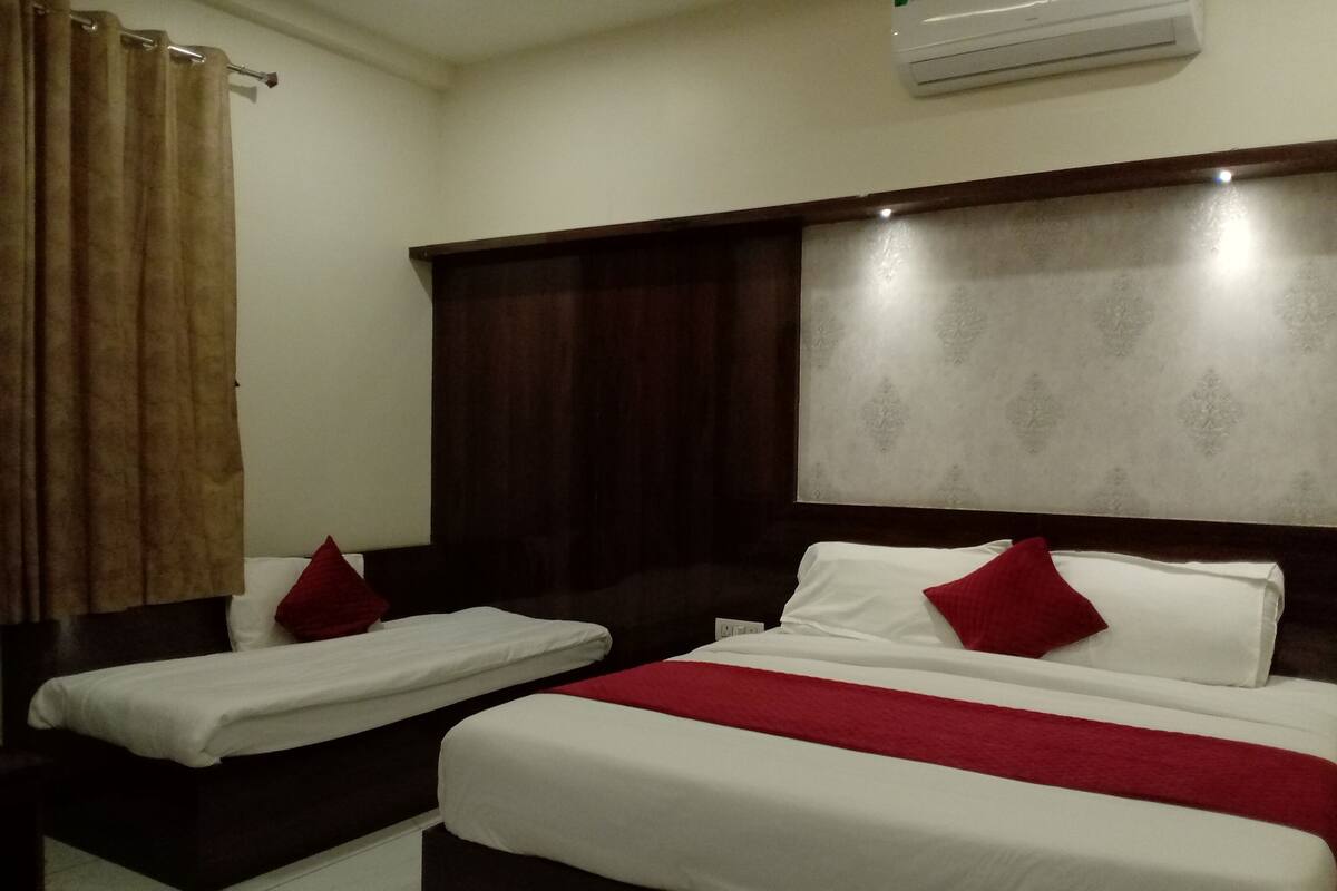 A hotel room with two single beds and a larger bed.