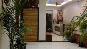 Un vestíbulo moderno con mostrador de recepción de madera, plantas en macetas, una araña y una escalera.