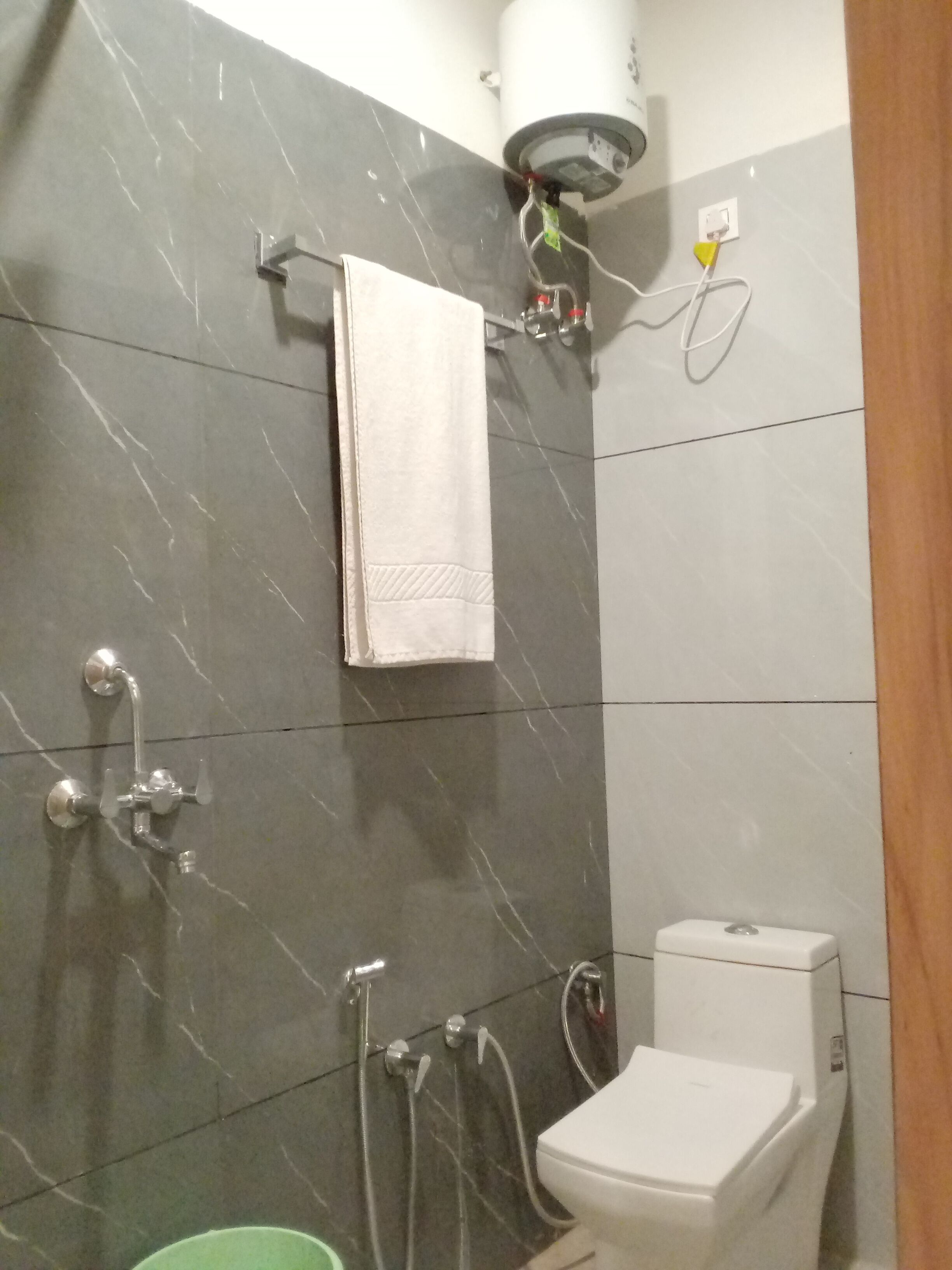 A bathroom with a shower, toilet, and a towel hanging on the wall.