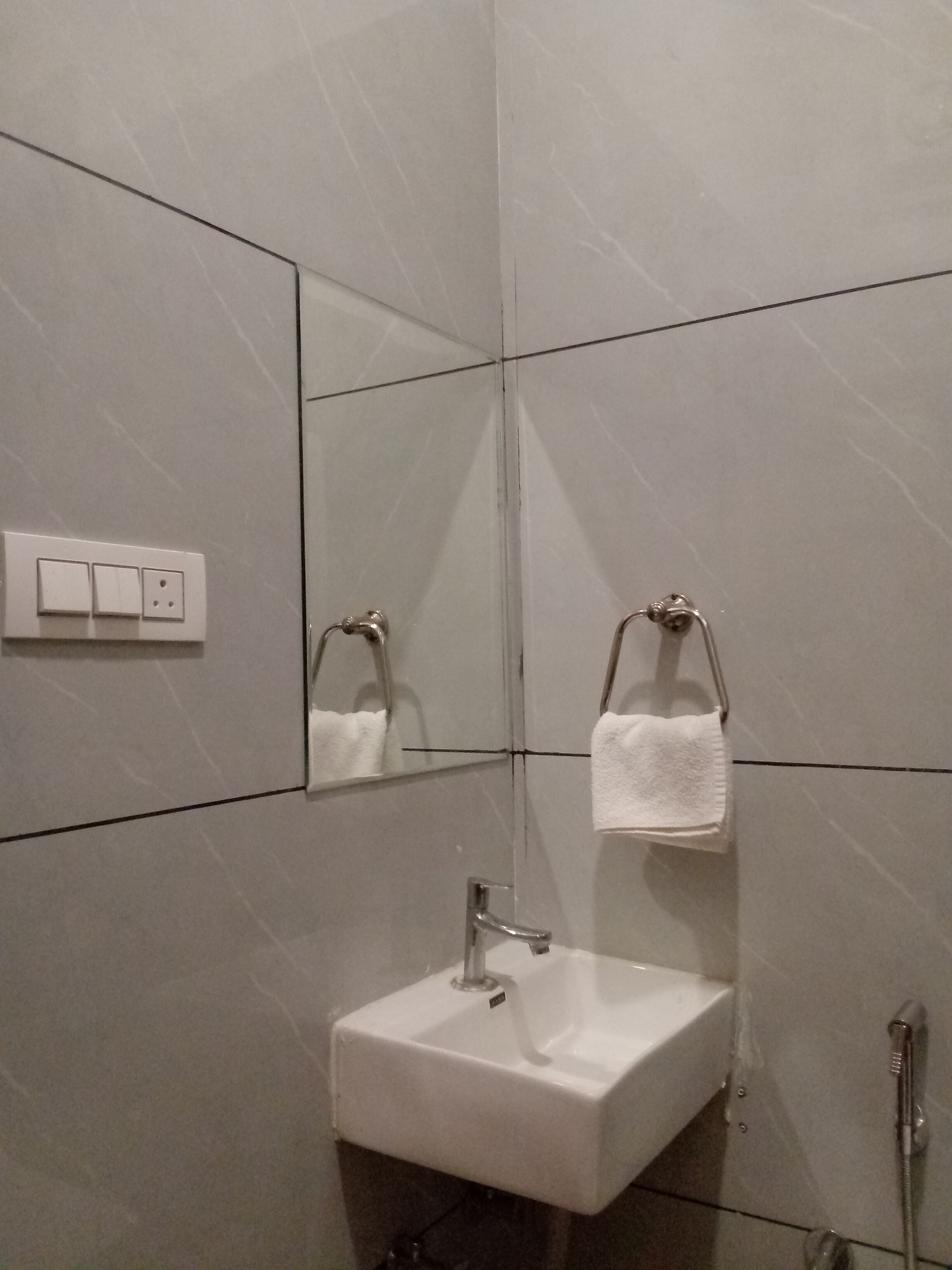 A modern bathroom with a white sink, a mirror, and a towel rack.