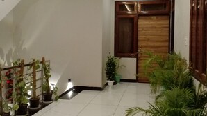 Un pasillo amplio con abanico de techo, plantas en macetas y una puerta de madera.