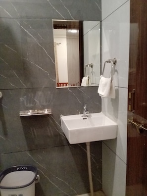 A bathroom with a white sink, a mirror, and a towel rack. - Hotel Pushkar Town (Pushkar)