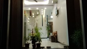 La entrada al Hotel Pushkar Town con un letrero sobre la puerta, un ventilador de techo y plantas en macetas.
