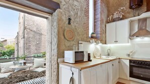 A compact kitchen with white cabinets, a built-in oven, and a microwave on the countertop. - Charming Stone House near Beach Retreat (Vilaür)