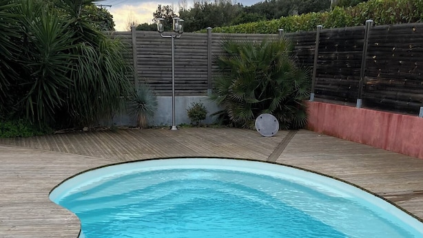 A clear blue swimming pool with a wooden deck surrounding it.