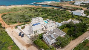 An aerial view of a coastal property with multiple buildings, a swimming pool, and a road leading to the sea. - Villa Regina on the Sea (Carovigno)