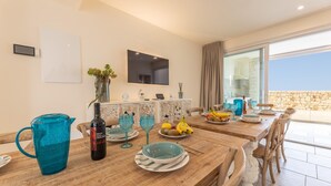 A dining area with a wooden table, blue glassware, and a TV mounted on the wall. - Villa Regina on the Sea (Carovigno)