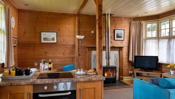 A cozy cabin interior with a kitchen, dining area, and living room. - Cottage by Mawddach Trail with Stunning Views (Dolgellau)