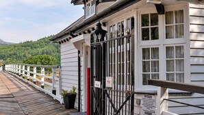 A wooden deck with a white railing, a black gate, and a sign that reads "PUSH PAID". - Cottage by Mawddach Trail with Stunning Views (Dolgellau)