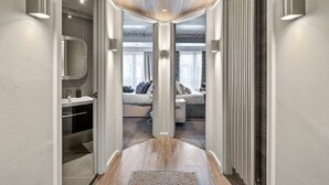A modern hallway with a wooden floor, a glass ceiling, and a view into a living area with a sofa and a fireplace. - Apartment in Dartmouth near Waterfront (Dartmouth)