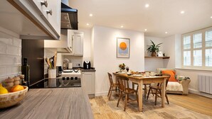 Una cocina moderna con comedor, armarios de madera y un amplio ventanal que proporciona luz natural.