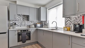 Une cuisine moderne avec des meubles gris, un four à micro-ondes, une bouilloire et une machine à café.