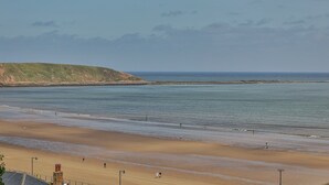A beach with a sandy shore, a grassy hill in the background, and a calm sea. - Apartment in Filey near the Beach (Filey)
