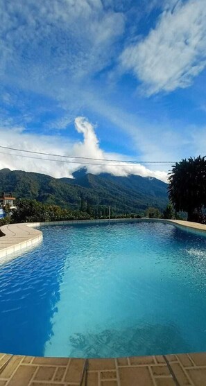 Una piscina con vistas a montañas y un cielo despejado.