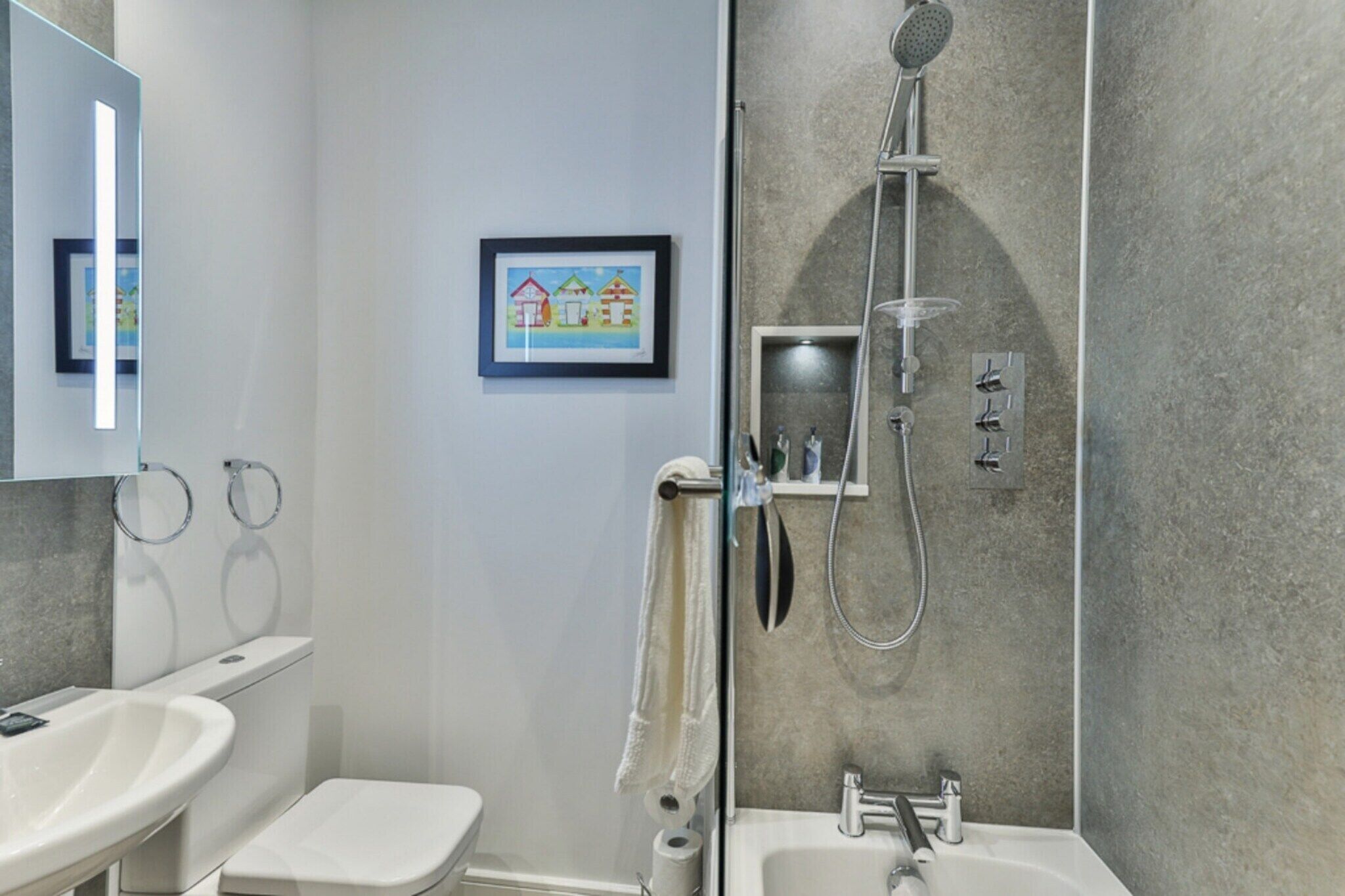 A modern bathroom with a shower, toilet, and sink.