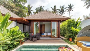 A poolside area with a covered seating area, a small table, and a lounge chair.