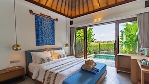 A modern bedroom with a large bed, a desk, and a view of a swimming pool.
