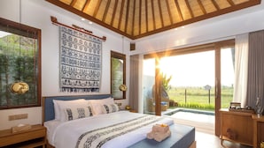 A spacious bedroom with a large bed, a view of a lush green field, and a wooden ceiling.